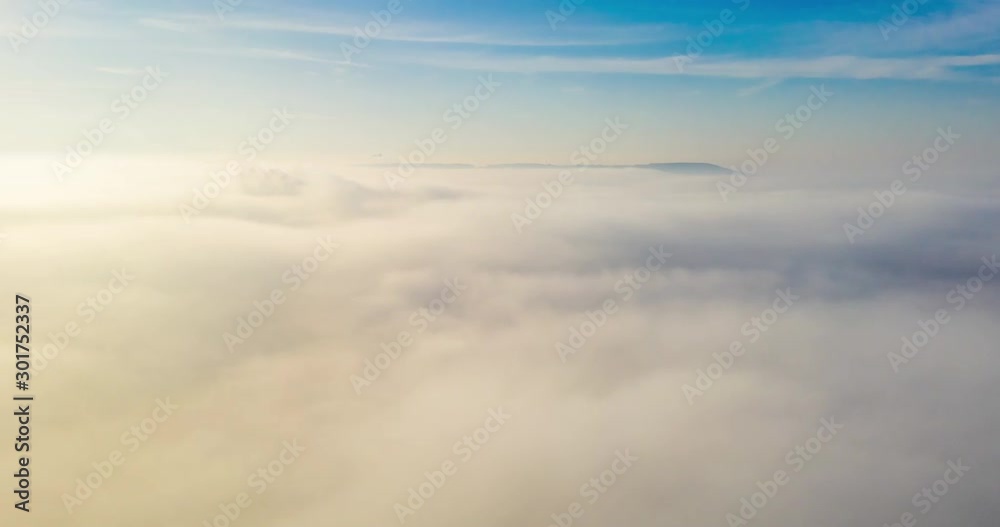 Timelapse view above the fog or white clouds with shining sun. Beautiful sunrise cloudy sky from aerial view. Above clouds from airplane window or drone. Timelapse view above the fog or white clouds with shining sun. Beautiful sunrise cloudy sky from aerial view. Above clouds from airplane window or drone.