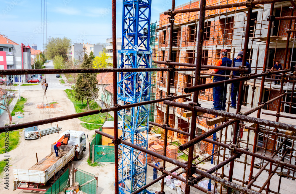 Workers are watching construction site from above, standing on scaffold