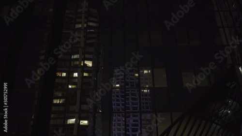 Skyscraper reflection with glass windows at business district in Paris at night, slow steadicam movement side track, Medium shot with reflections. Futuristic modern building with lights. 4K UHD.