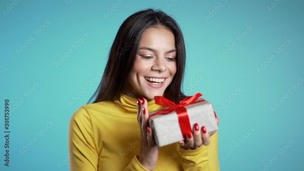 Excited woman received gift box with bow. She is happy and flattered by attention. Girl on blue background. Studio footage. Excited woman received gift box with bow. She is happy and flattered by attention. Girl on blue background. Studio footage.