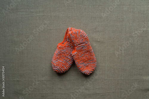 A pair of orange knitted slippers lying on a linen art canvas