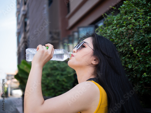 Asian tourist woman drinking a bottle of water in Hua Hin city, travel concept.