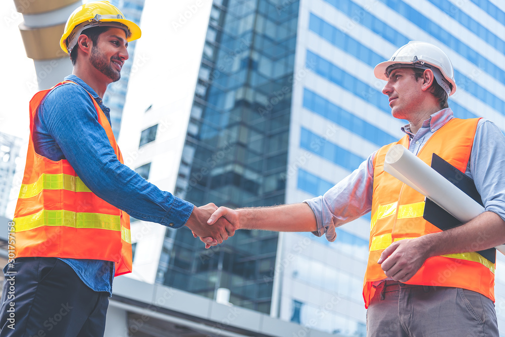 Engineer in Yellow helmet and best greeting with warm handshake manager visiting site. Modern construction and engineering concept. Safety of work in production and construction work place. Engineer in Yellow helmet and best greeting with warm handshake manager visiting site. Modern construction and engineering concept. Safety of work in production and construction work place.