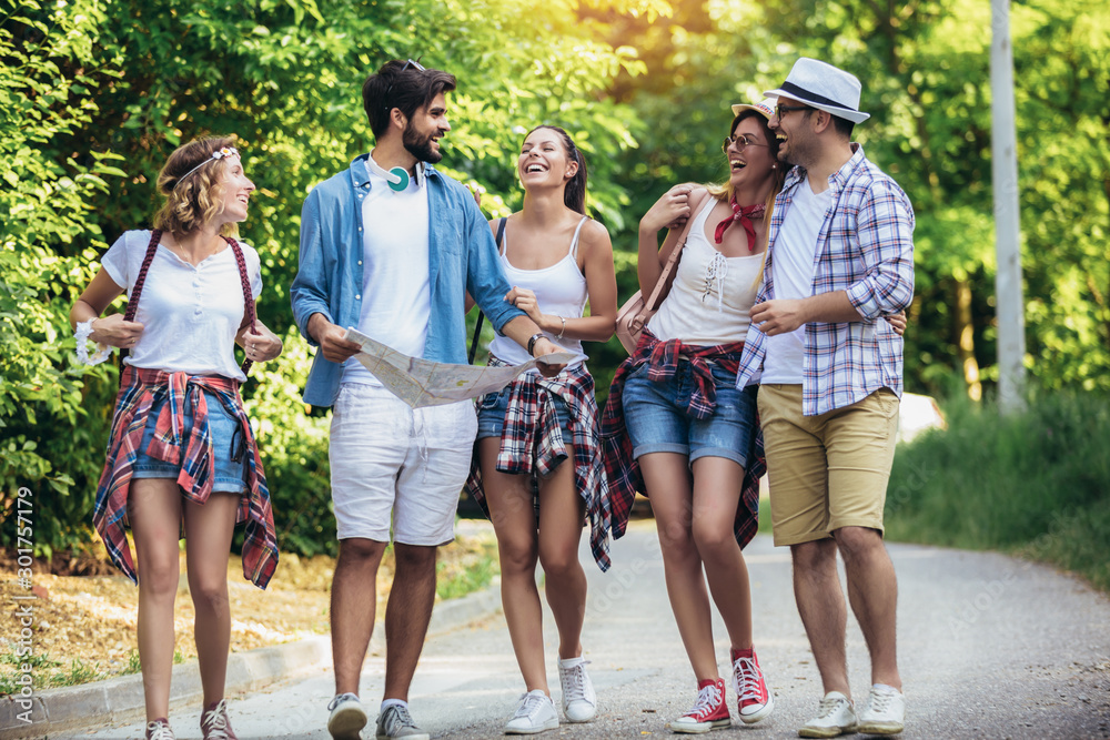Obraz premium Group of young people with backpacks walking together and looking happy