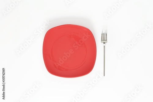 Empty Dark Blush Red color plate and fork next to it. Isolated object - on white background