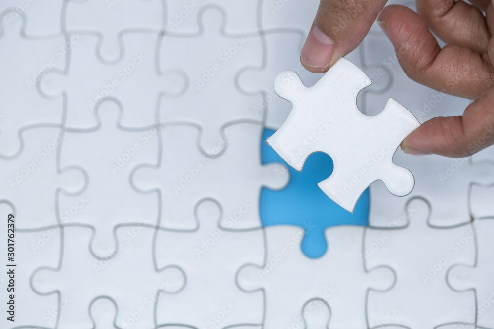 Hand put the last piece of jigsaw puzzle to complete the mission Hand put the last piece of jigsaw puzzle to complete the mission