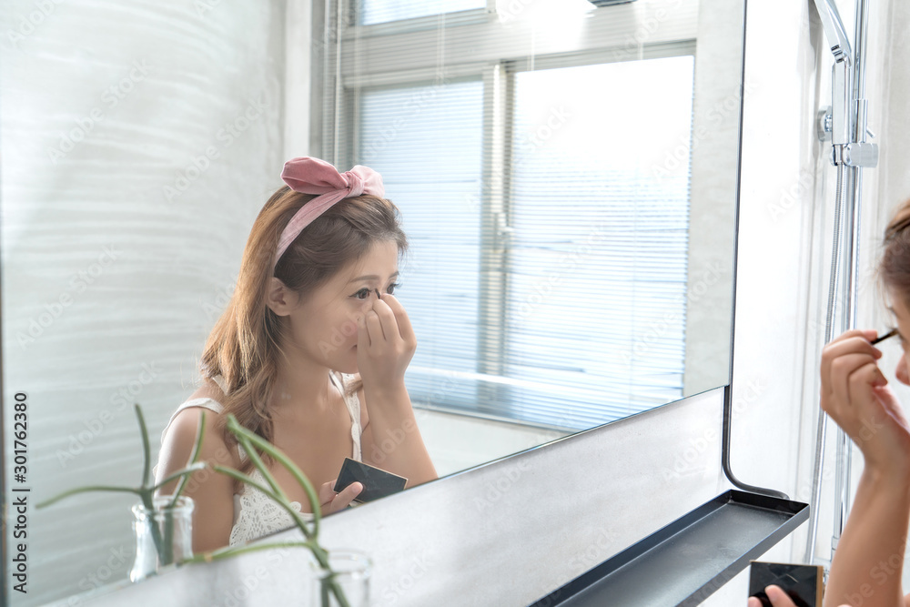 Close up of Smile woman with makeup brushes near face and look mirror. asian beauty Close up of Smile woman with makeup brushes near face and look mirror. asian beauty