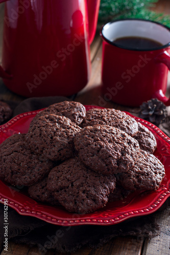 Chocolate plain cookies on a red plate on a wooden table, selective focus