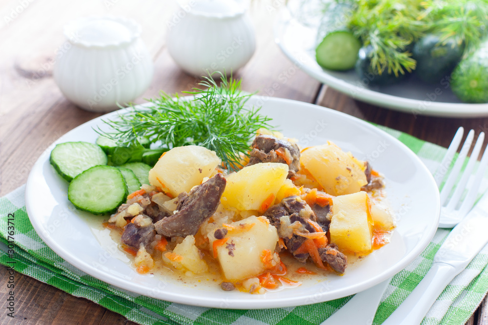 Stewed potatoes with chicken liver and carrots on a white plate, selective focus Stewed potatoes with chicken liver and carrots on a white plate, selective focus