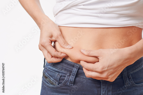 Woman checking her waist for excess weight pinching her skin between her fingers