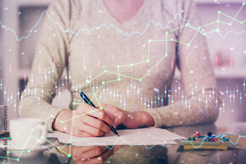 Hand taking notes in notepad. Forex chart holograms in front. Concept of research. Double exposure