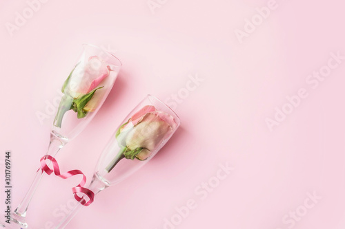 Roses in wineglasses on a pink background. Background for holiday, birthday, wedding, Valentine's day, Women's Day. Top view, flat lay composition. Copy space for text or design. © Lyubov