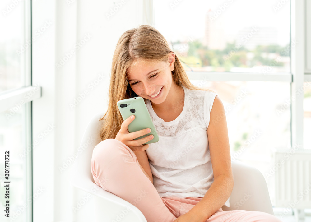 Teen girl spending leisure with her smartphone indoors Teen girl spending leisure with her smartphone indoors