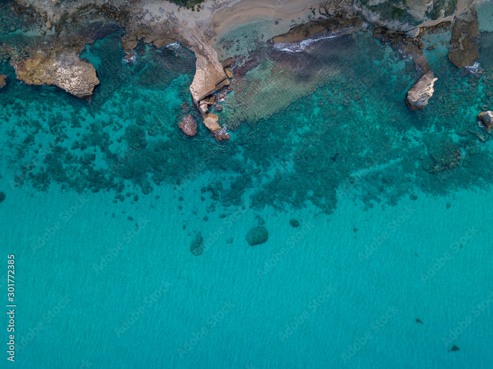 Aerial view of a seabed with rocks emerging from the sea, seabed seen from above, transparent water and beach