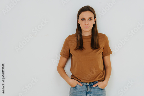 Portrait of a woman, leaning on the wall, with hands in pockets. Half length