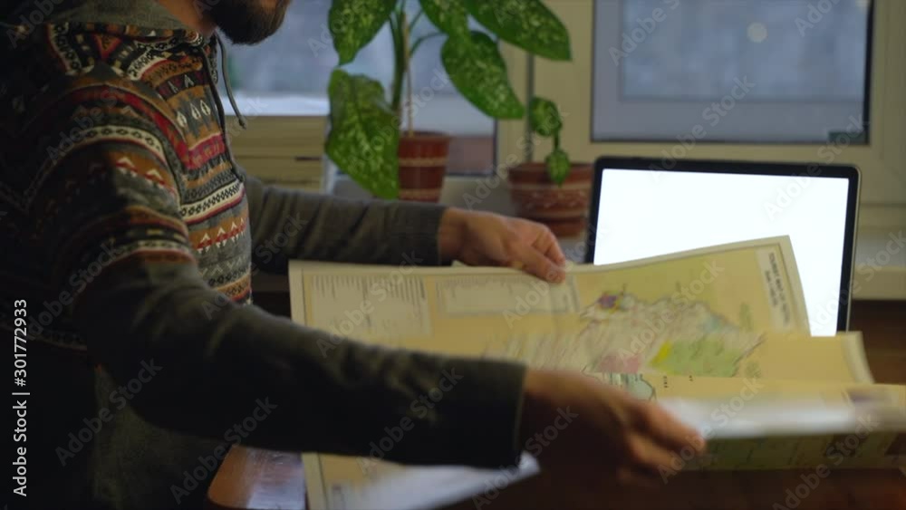 A young traveler prepares for a new trip and opens a map to get acquainted with the new country. A young traveler prepares for a new trip and opens a map to get acquainted with the new country.