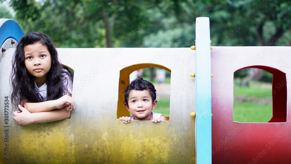 Three Asian children, two men, one girl Playing in the outdoor garden. Concept. Sitting on a colorful train.                              