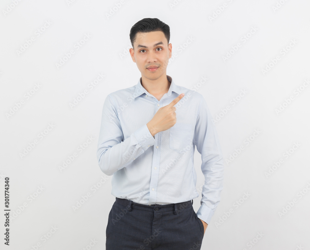 Young asian business man with blue shirt pointing to the side with a finger to present a product or an idea while looking to camera isolated on white background. Young asian business man with blue shirt pointing to the side with a finger to present a product or an idea while looking to camera isolated on white background.