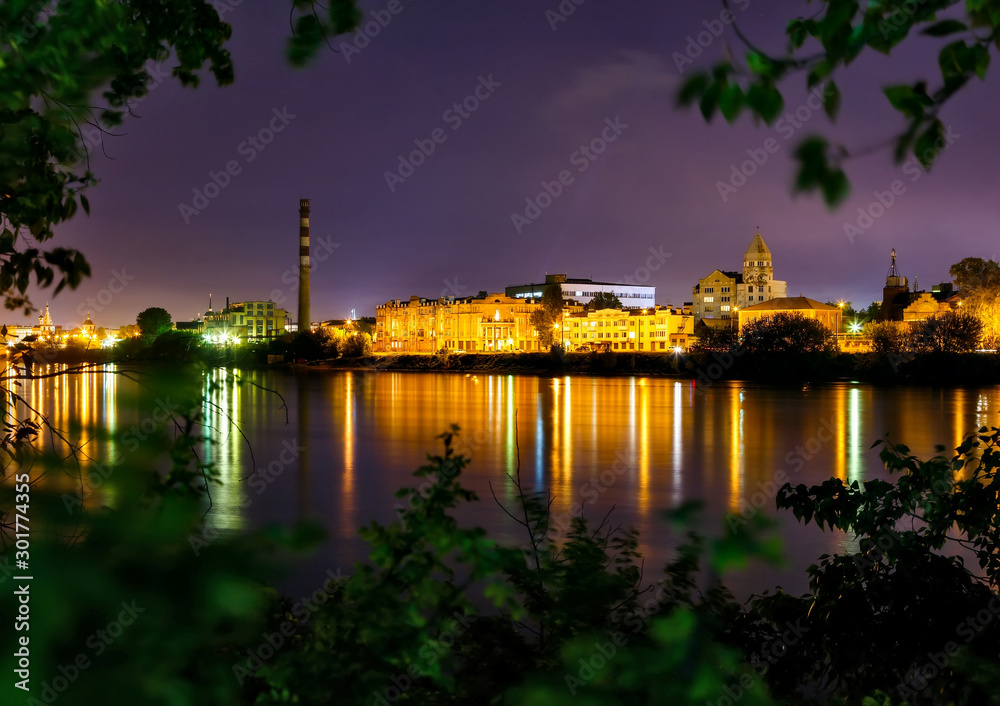 Industrial cityscape of Irkutsk with factory pipe at night at the bank of the river