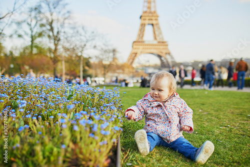 One year old girl sitting on the grass with blue flowers and Eiffel tower © Ekaterina Pokrovsky