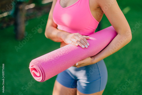 Young woman holds yoga mat in hand, close-up