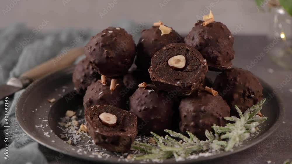 Dark chocolate truffles with hazelnuts and chopped hazelnuts over wooden cutting board. Dark chocolate truffles with hazelnuts and chopped hazelnuts over wooden cutting board.