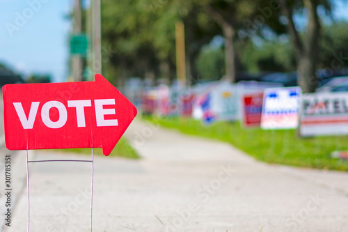Sign directing voters to a polling place with a row of political signs in the background. photo