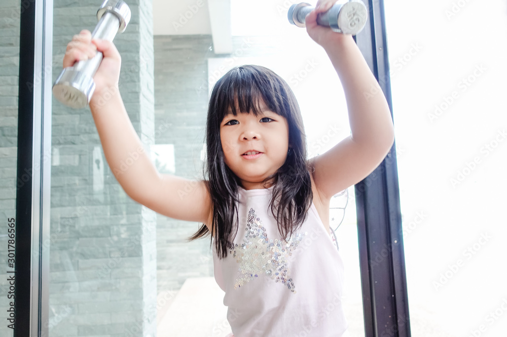 Little asian girl working out with dumbbells at gym and tired face. Little asian girl working out with dumbbells at gym and tired face.