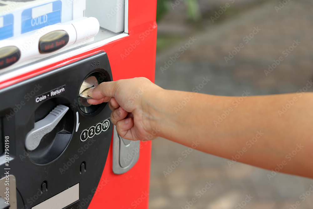 The woman's hand is insert coin an automatic water dispenser to buy soft drinks. The woman's hand is insert coin an automatic water dispenser to buy soft drinks.