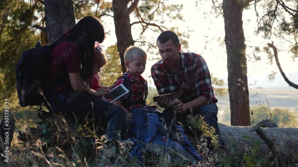 Happy family with tablet computer in the forest. A family trip with modern technology. Happy family concept Happy family with tablet computer in the forest. A family trip with modern technology. Happy family concept