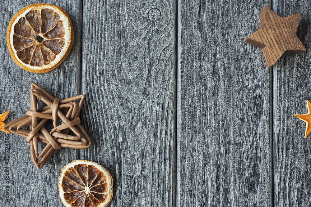 A gray textured wooden background on which dried orange slices and stars. space for text... A gray textured wooden background on which dried orange slices and stars. space for text...