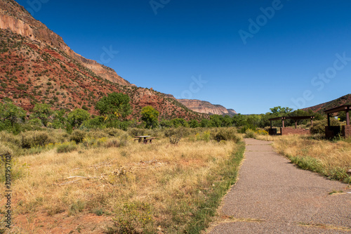 Landscape of walking path, greenery and multi-colored stone hillside near Jemez Springs in New Mexico
