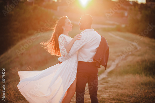 mixed couple of people hugging on sunset background