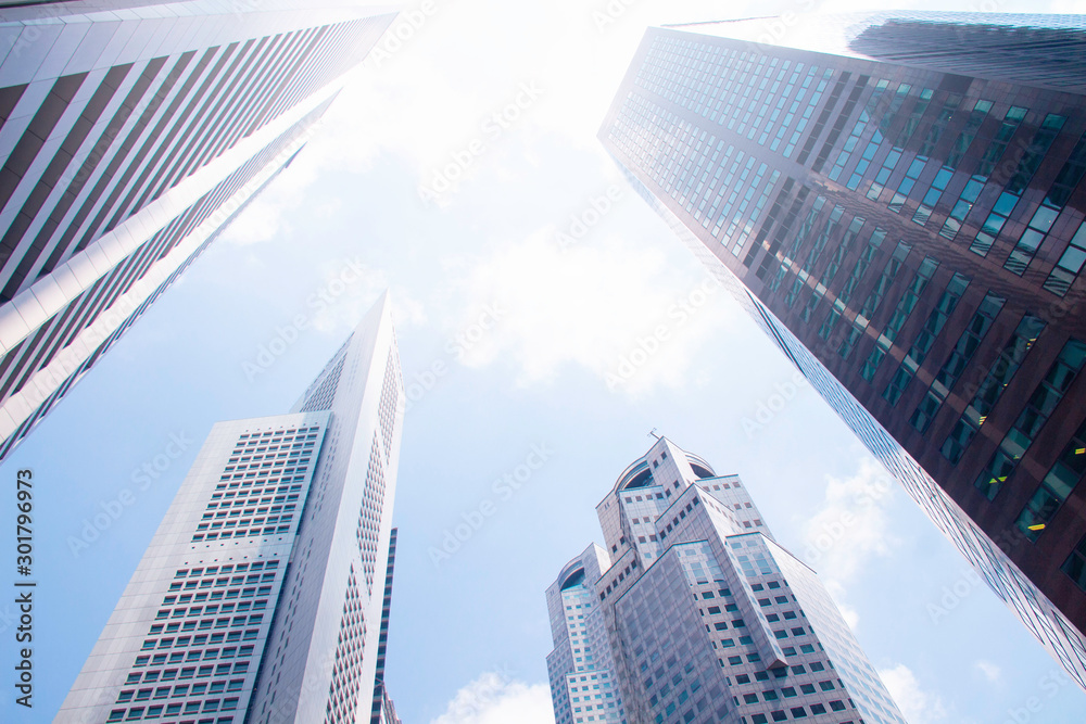 Bottom view of modern skyscrapers/office buildings in the business district of Singapore cities against the blue sky. Economy, finances, business activity concept.