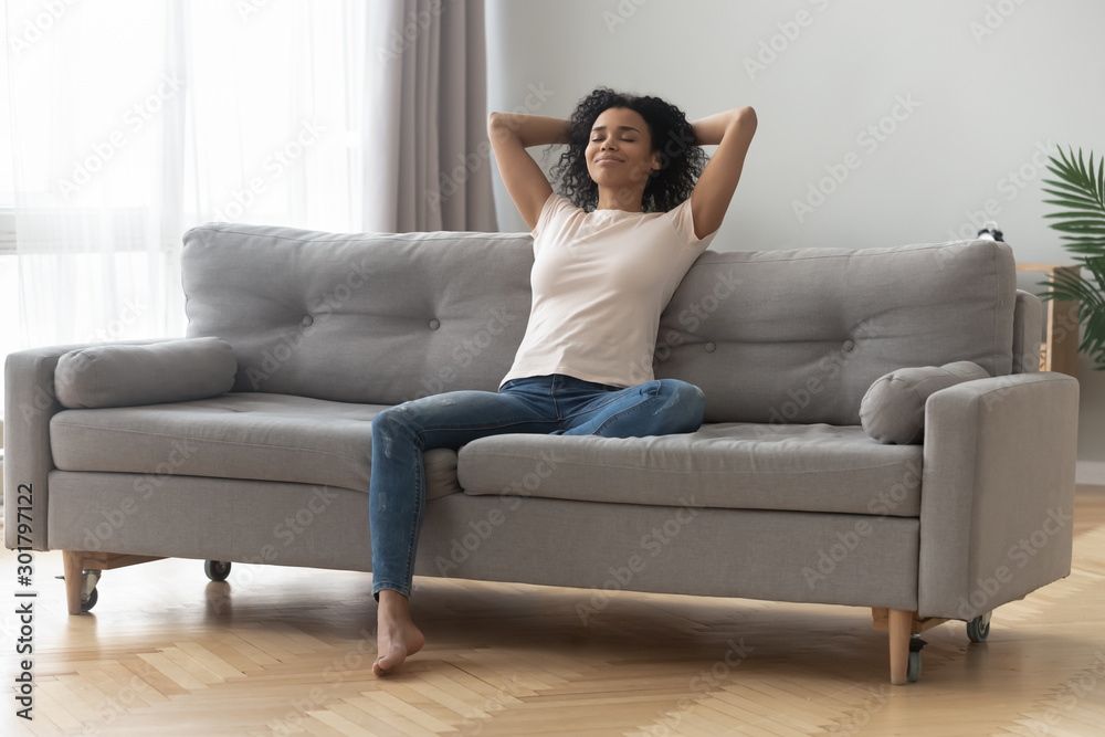 Satisfied African American woman with closed eyes relaxing on couch Satisfied African American woman with closed eyes relaxing on couch