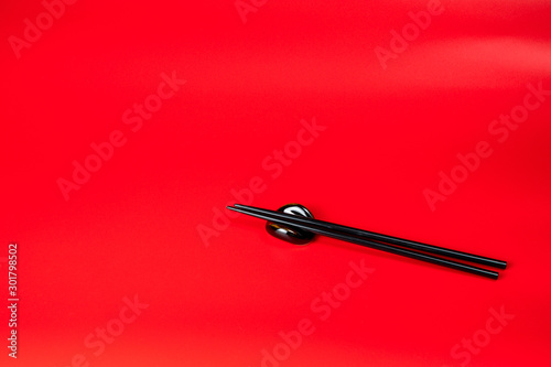 Black chopsticks with holder on red background