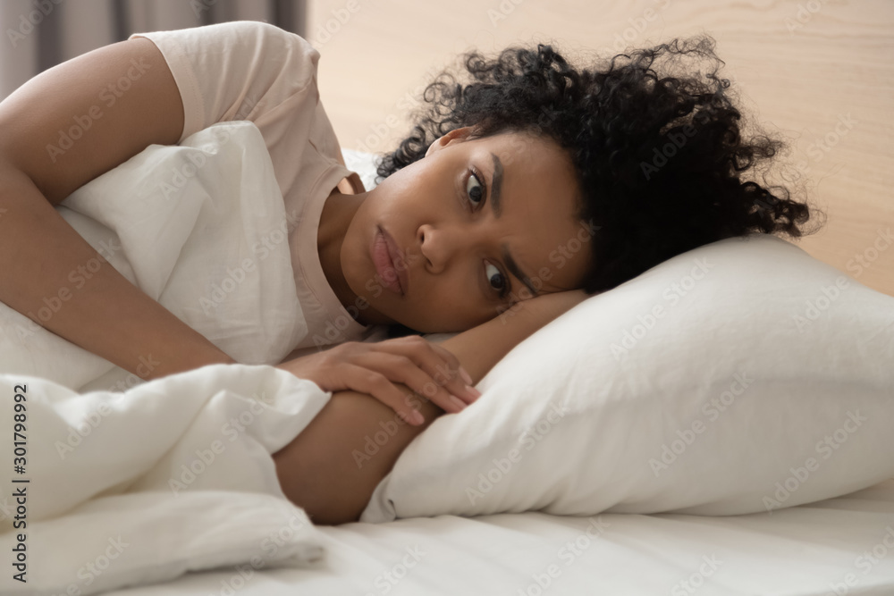 Unhappy African American woman suffering from insomnia, lying in bed - obrazy, fototapety, plakaty 