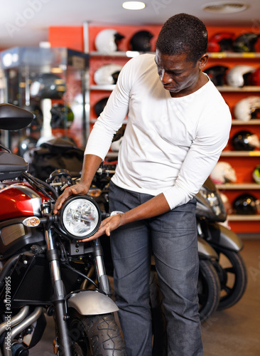 Portrait of young man buying new motorcycle at modern showroom