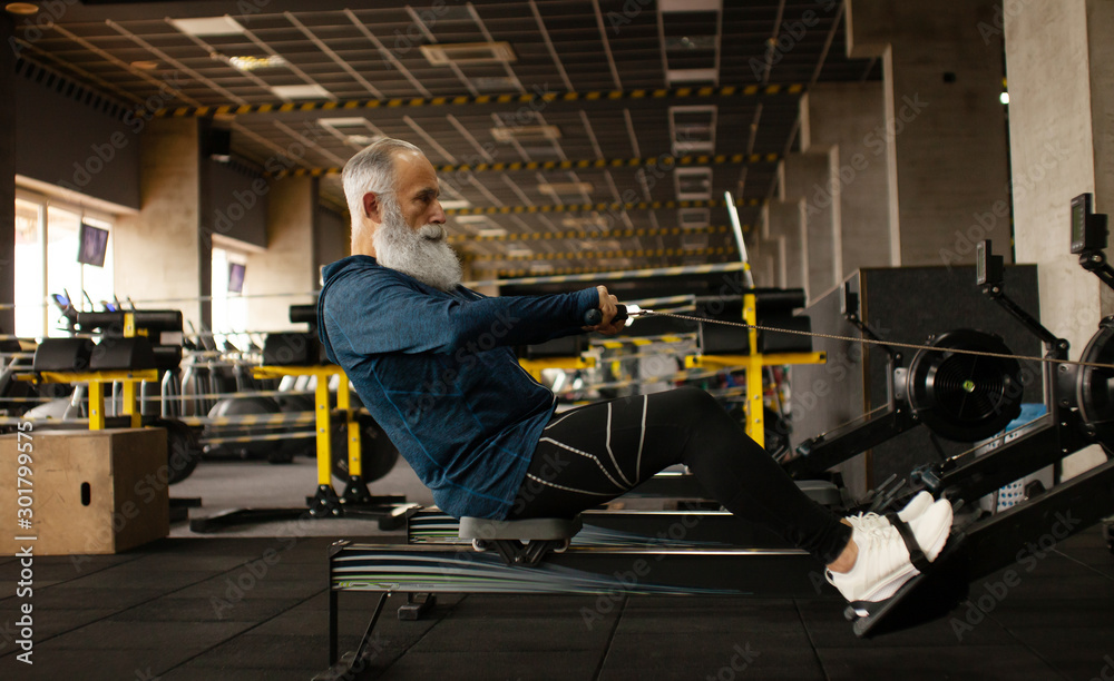 Serious mature male is having intense workout in gym. Serious mature male is having intense workout in gym.
