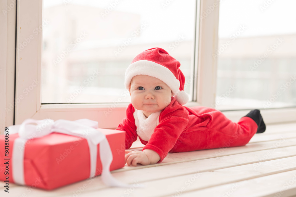 Beautiful little baby celebrates Christmas. New Year's holidays. Baby in a Christmas costume and in santa hat Beautiful little baby celebrates Christmas. New Year's holidays. Baby in a Christmas costume and in santa hat