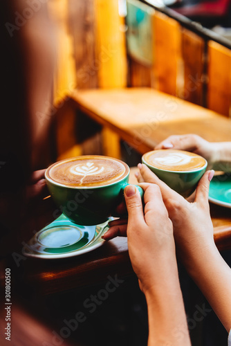 Drinking coffee together. two beautiful woman keeping cups of coffee.