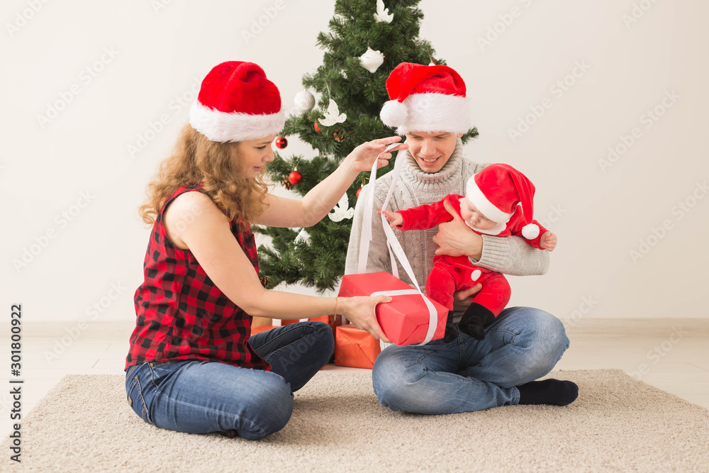 Happy couple with baby celebrating Christmas together at home. Happy couple with baby celebrating Christmas together at home.