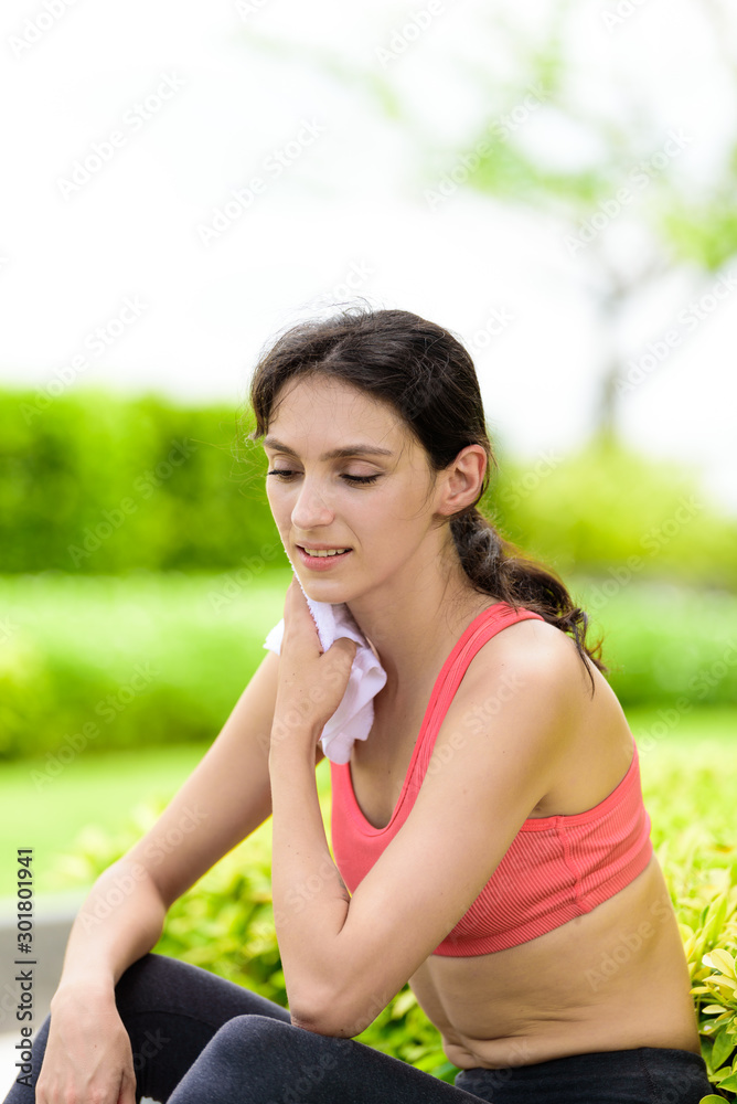 Beautiful woman runner has used a white towel wipe her face after running in the garden. Beautiful woman runner has used a white towel wipe her face after running in the garden.