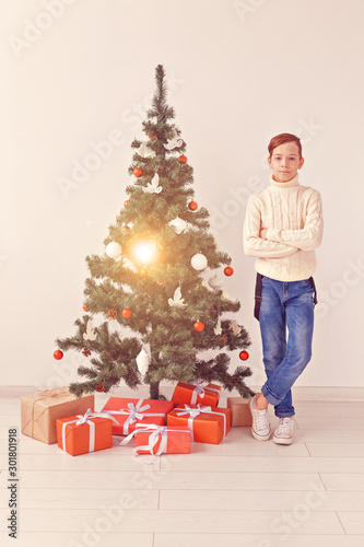 holidays and winter childhood concept - smiling teen boy standing near christmas tree on white background