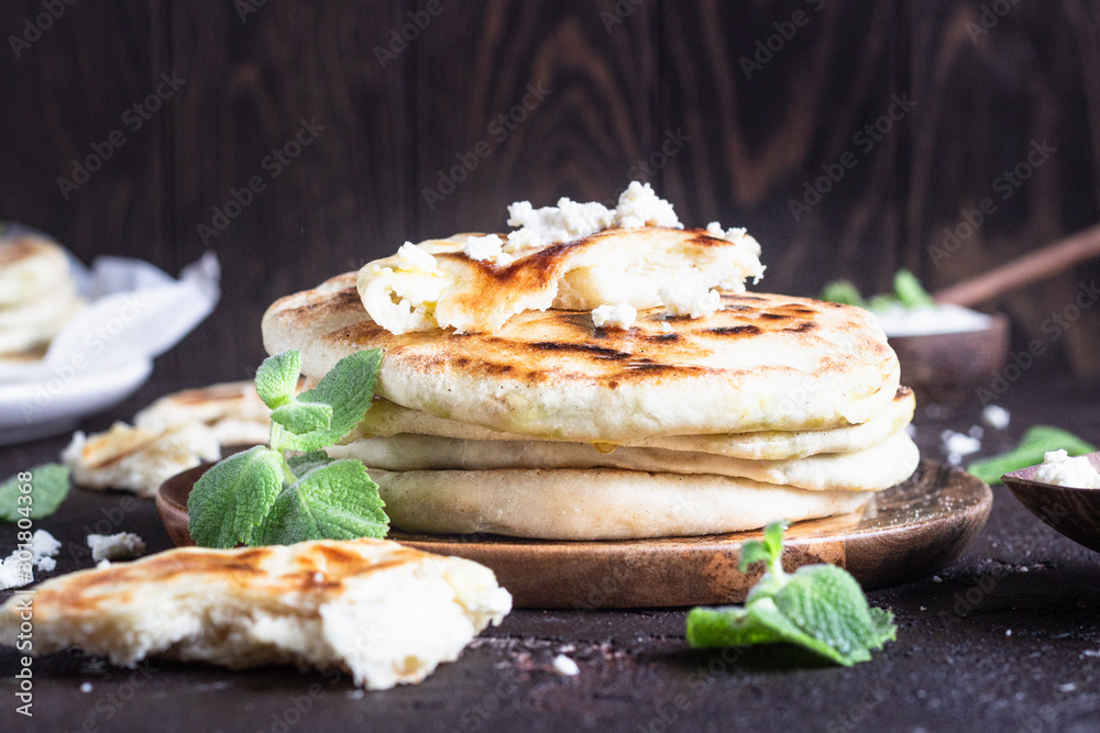 Onion, mint and cheese small flatbreads served on a wooden plate. Gozleme - crispy, golden Turkish flatbreads. Onion, mint and cheese small flatbreads served on a wooden plate. Gozleme - crispy, golden Turkish flatbreads.