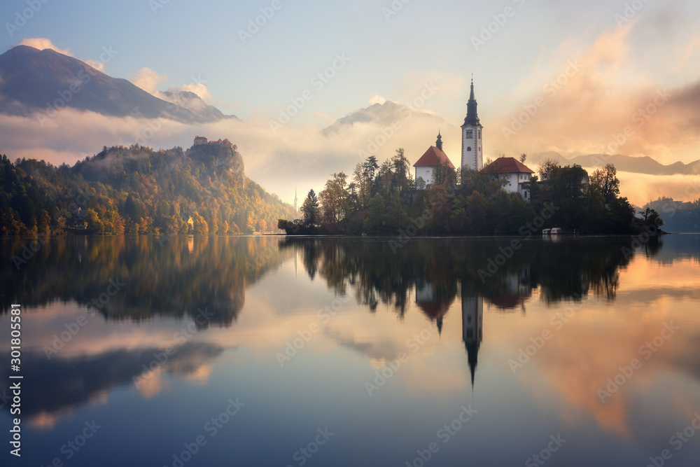 Stunning sunrise on Bled lake in Slovenia with the Pilgrimage Church of the Assumption of Maria and Bled Castle in the background