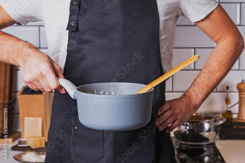 Unrecognizable man holding a pot with soup or stew on his kitchen
