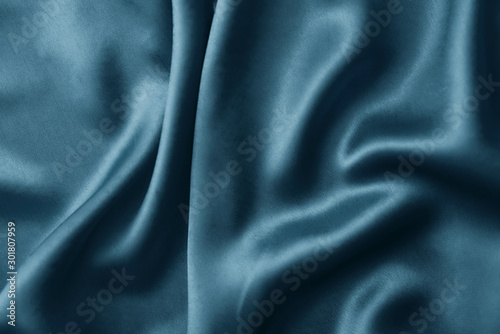 Silver silk background with a folds. Abstract texture of rippled silk surface