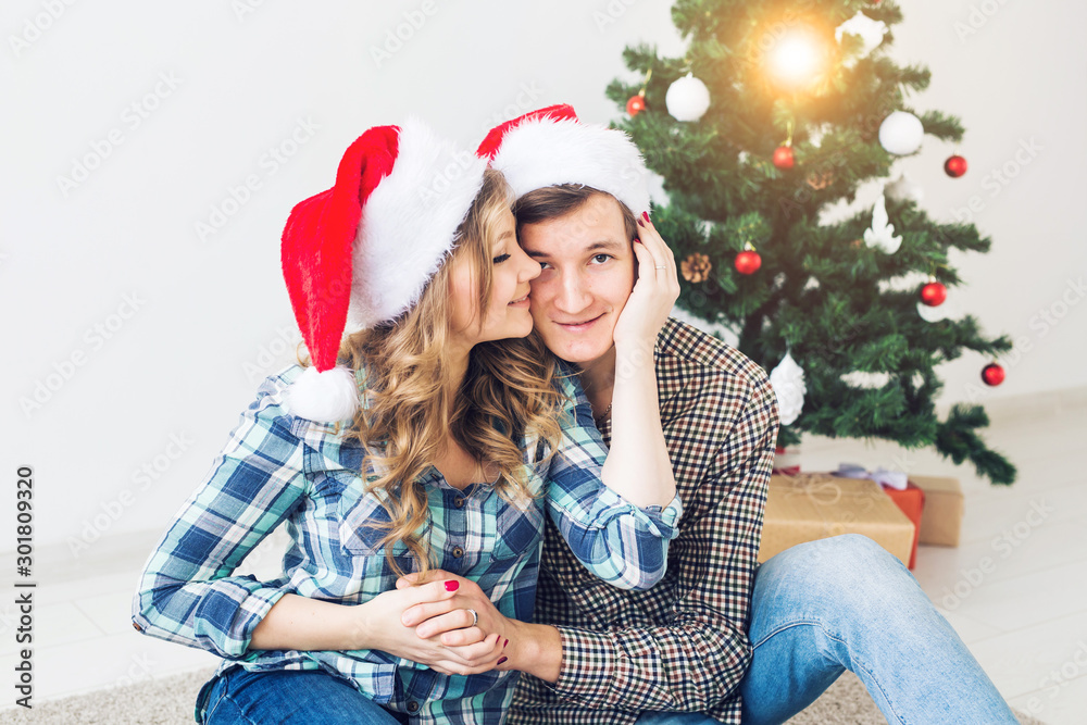 Family, x-mas, winter holidays and people concept - happy couple hugging near christmas tree at home Family, x-mas, winter holidays and people concept - happy couple hugging near christmas tree at home