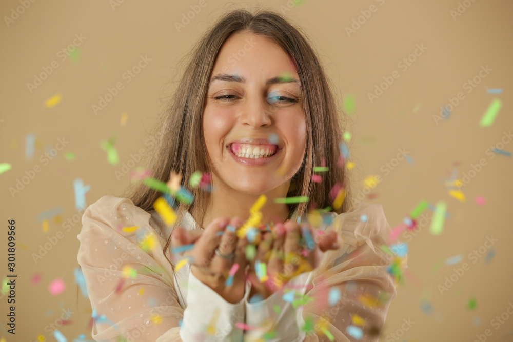 Portrait of a beautiful young woman with hands full of colorful confetti, party and holiday concept